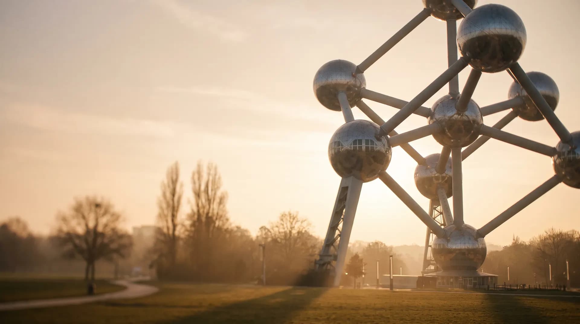 The Atomium's silver spheres rising above a Brussels park at golden hour