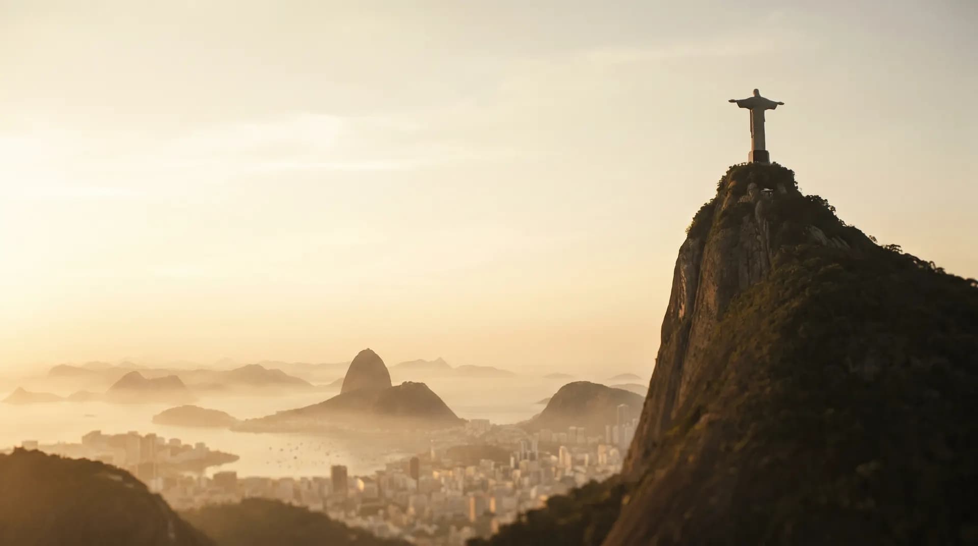Christ the Redeemer atop Corcovado above misty Rio de Janeiro at golden hour