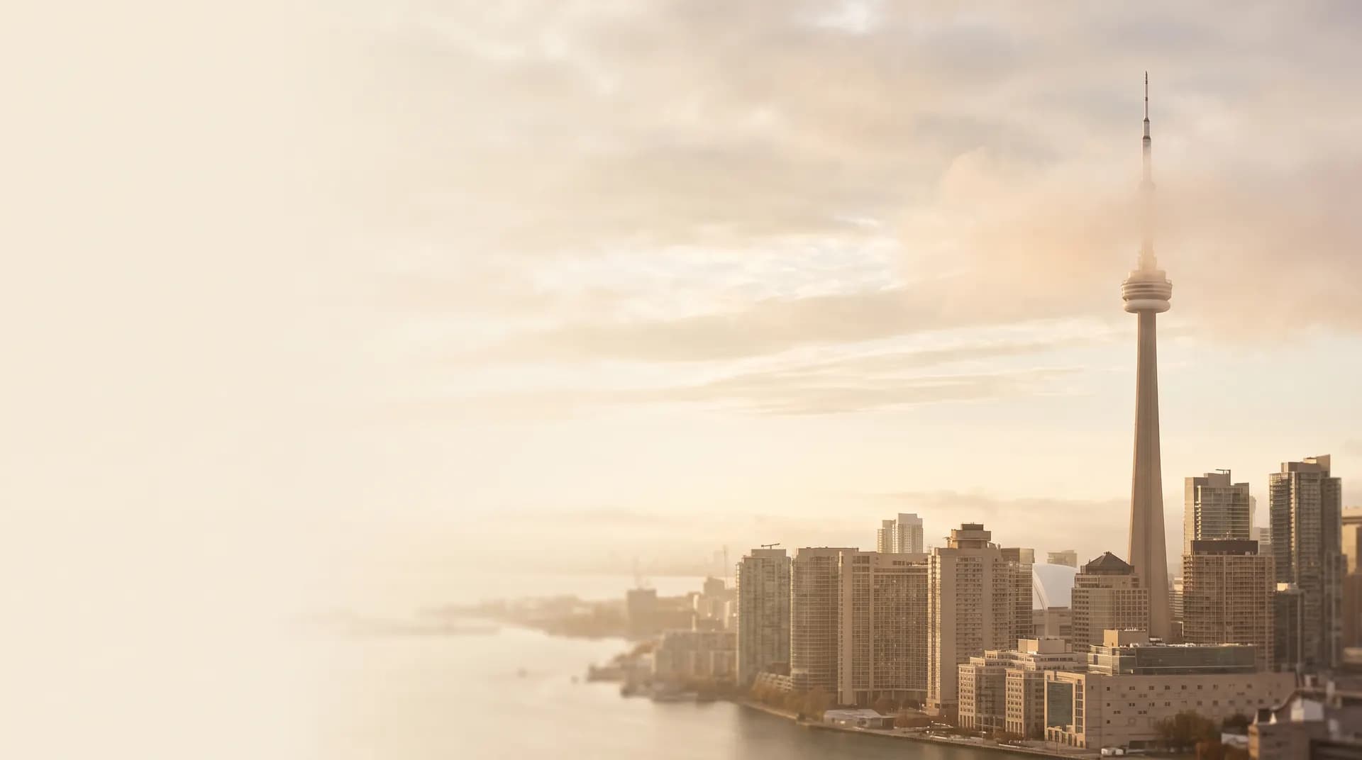 The CN Tower above the misty Toronto skyline at golden hour