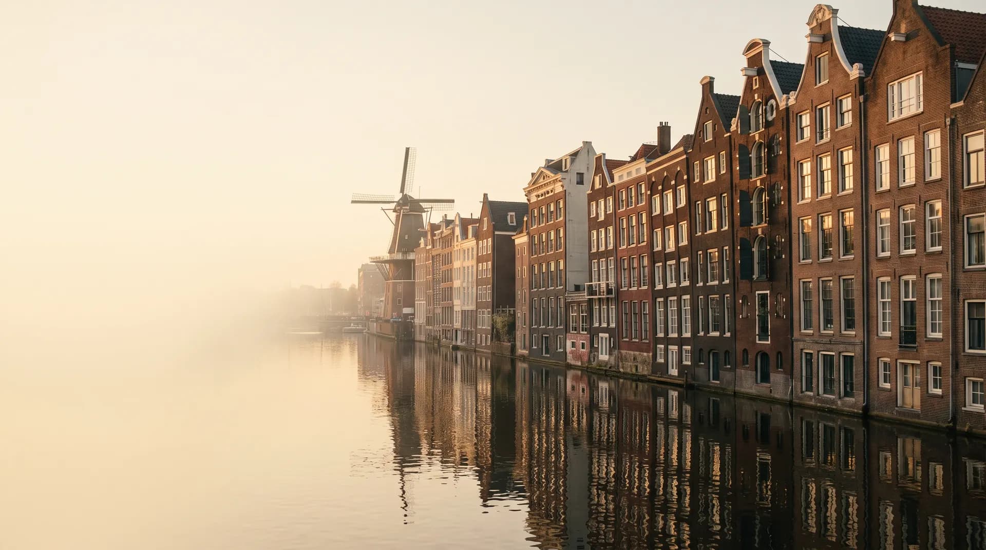 Amsterdam's gabled canal houses and a distant windmill at golden hour