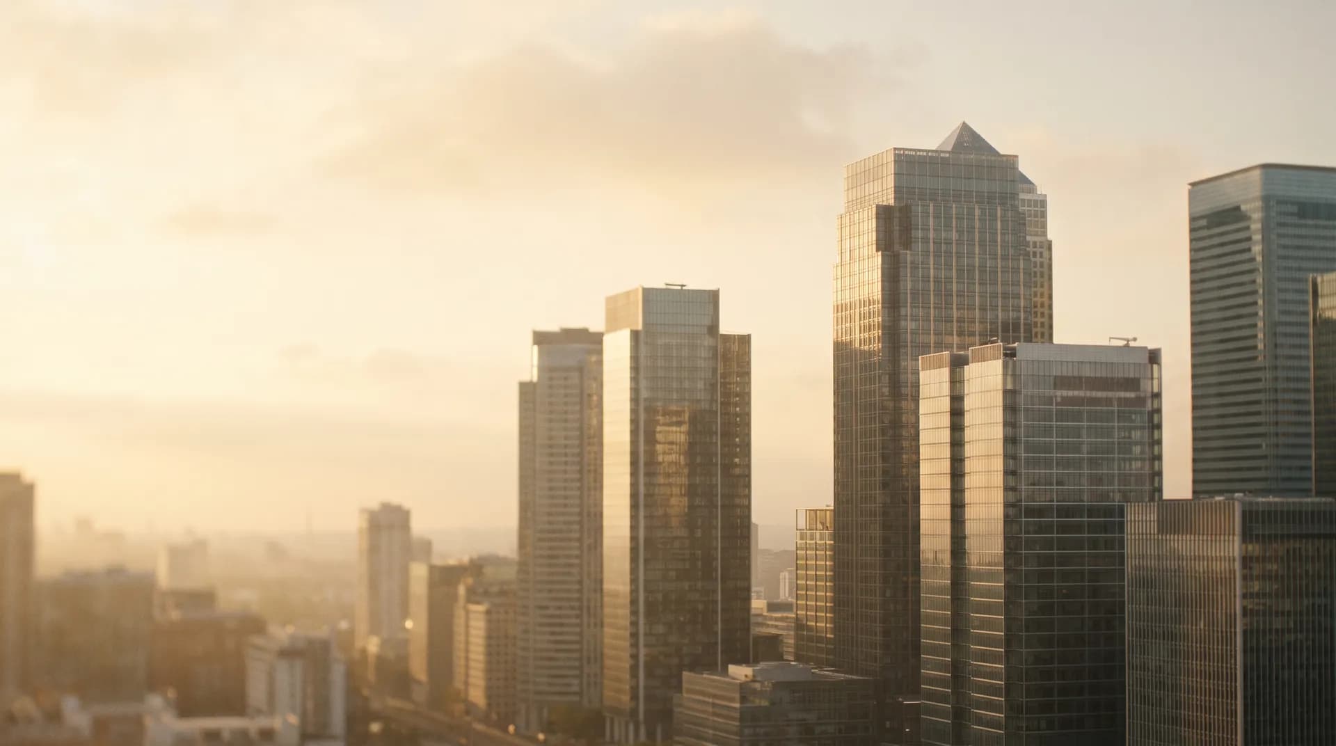 A hazy glass-and-steel financial district skyline at golden hour